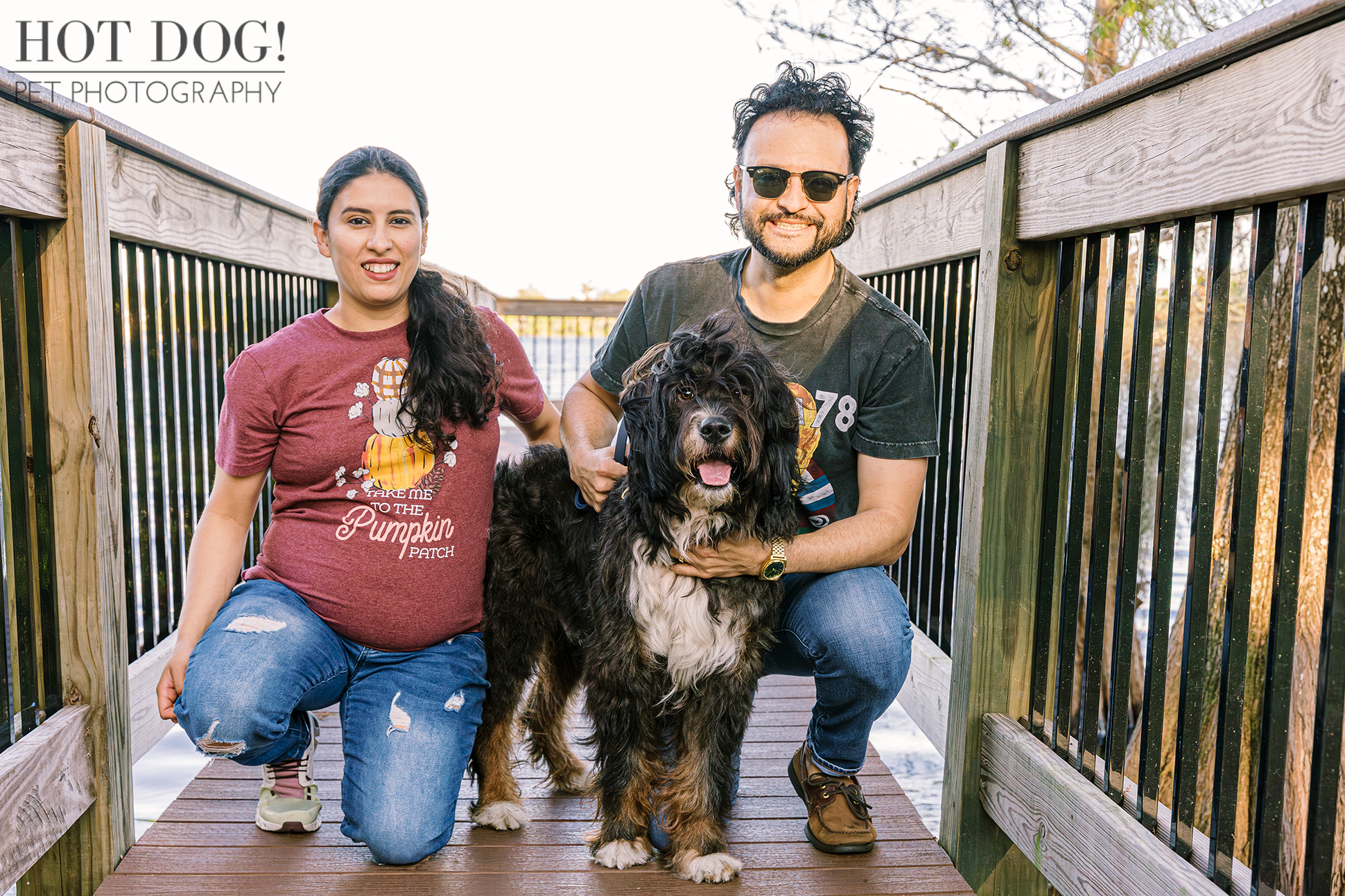 Happy family portrait: Gen and Fernando smile with their dog, Aspen the Bernedoodle, who sits between them.