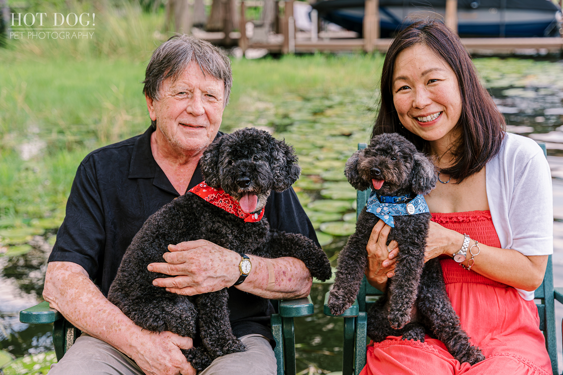 A happy couple poses with their two black poodles, showcasing a loving bond in a cozy environment.